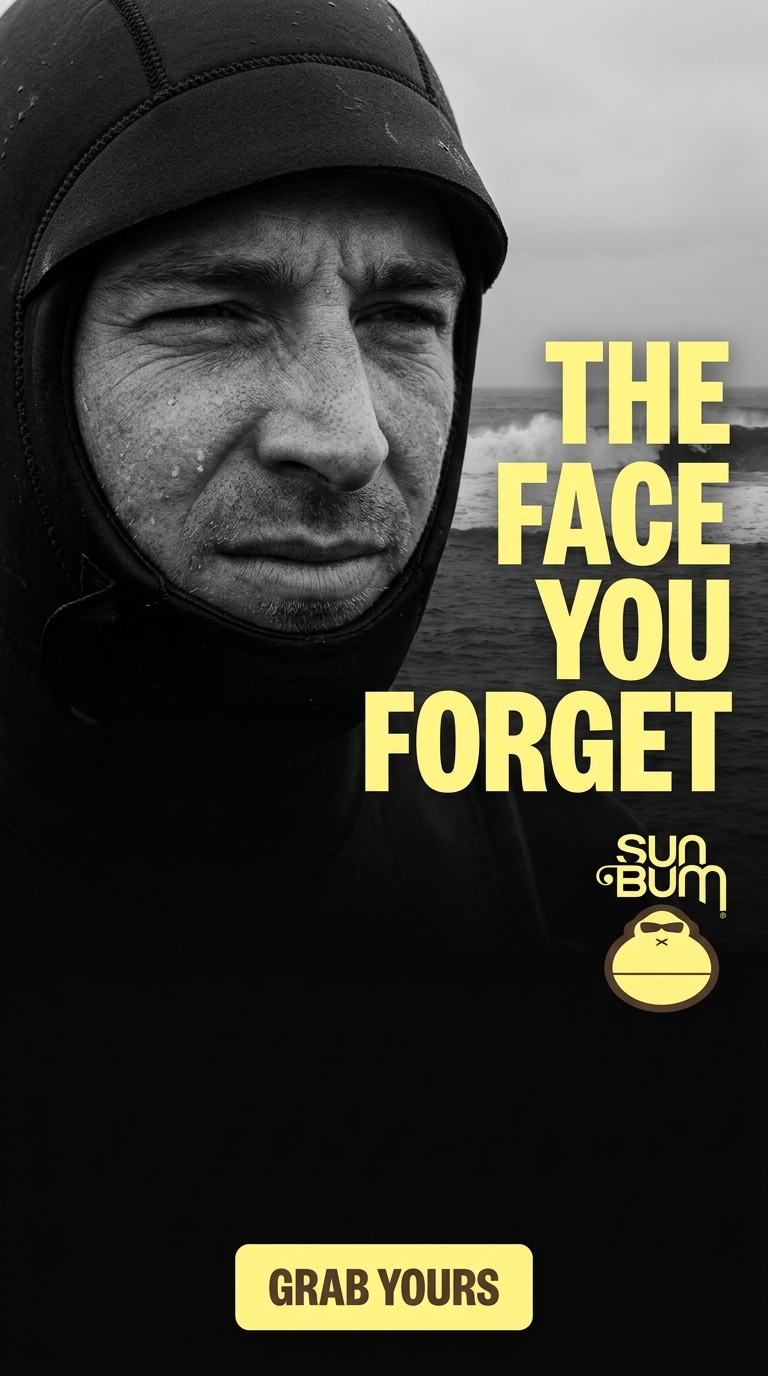 Raw, intimate black-and-white photography with desaturated tones. Focus on the surfer's face emerging from the hood, eyes squinting against Atlantic wind. Bold graphic composition merges the human subject with natural elements, naturalistic lighting sculpting every line of effort and exposure.